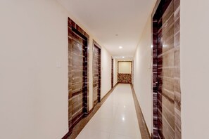 A hallway with a tiled floor, wooden doors, and a patterned wall at the end.