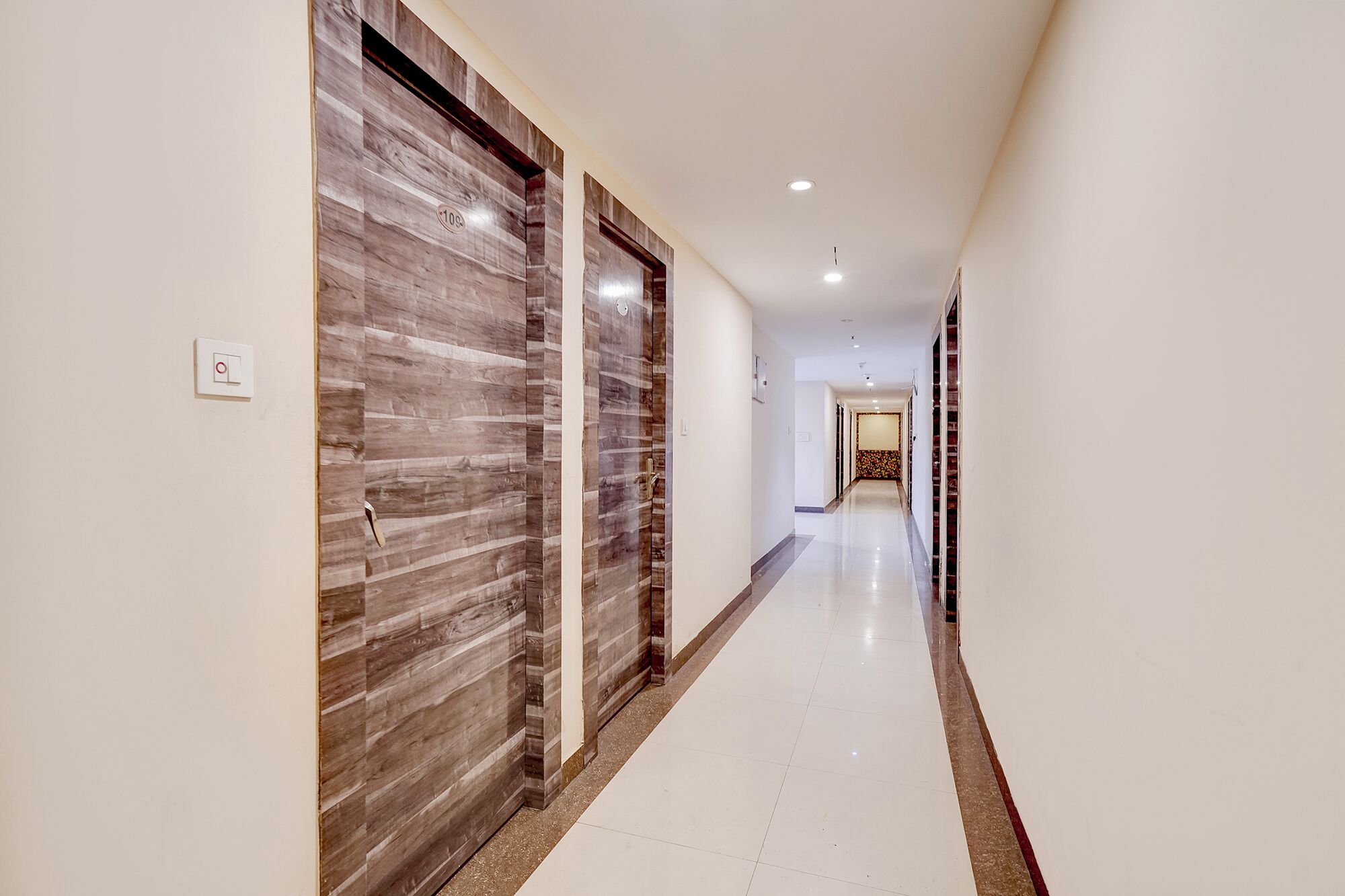 A hallway with a wooden door on the left and a white door on the right.