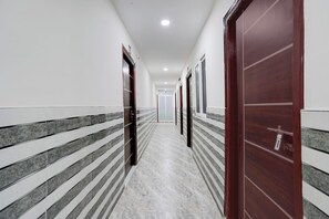 A corridor with doors on both sides, a tiled floor, and a ceiling with recessed lighting. - Fabhotel Olympio (Hyderabad)