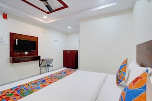 A hotel room with a bed, a TV mounted on the wall, a wardrobe, and a small table with a chair. - Fabhotel Olympio (Hyderabad)