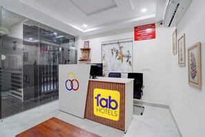 A hotel reception desk with a logo, a check-out sign, and a wall-mounted sign with check-out times. - FabHotel Olympio (Hyderabad)