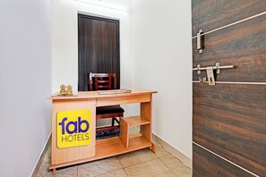 A small room with a wooden desk, a chair, a dark wooden door, and a sign for 'fab hotels'. - FabHotel Gita Residency (Visakhapatnam)