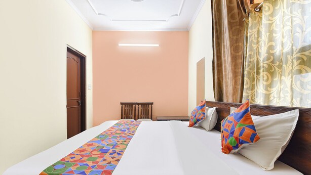 A hotel room with a bed, a bedside table, a chair, and a window with curtains.