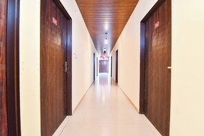 A hotel corridor with wooden doors and a tiled floor. - FabHotel Kartik Inn (Jaipur)