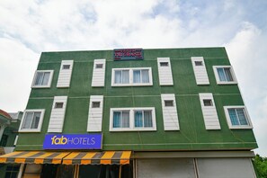 A multi-story building with a green facade and white window shutters. A sign indicates it is a hotel named 'TSJG Grand'. - FabHotel Tsj Grand (Indore)