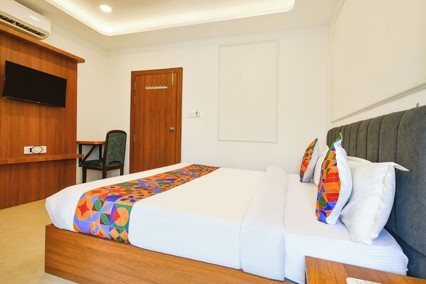 A hotel room with a bed, a television, a desk, and a chair.