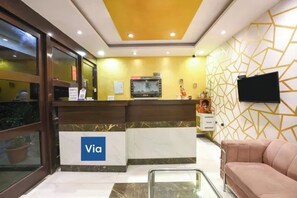 A reception area with a marble counter, a television, and a patterned wall. - FabHotel Under Bridge (New Delhi)