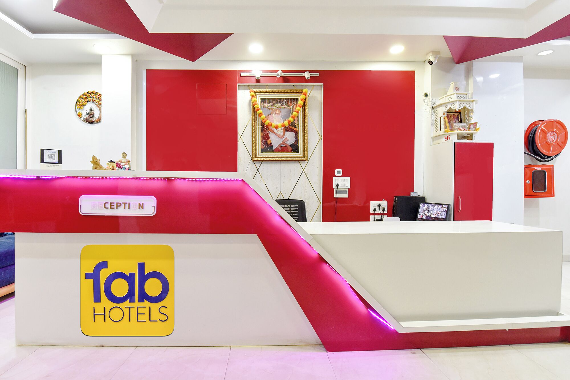 A reception desk with a 'fab hotels' sign, a 'CEPTION' label, and a framed picture on the wall.