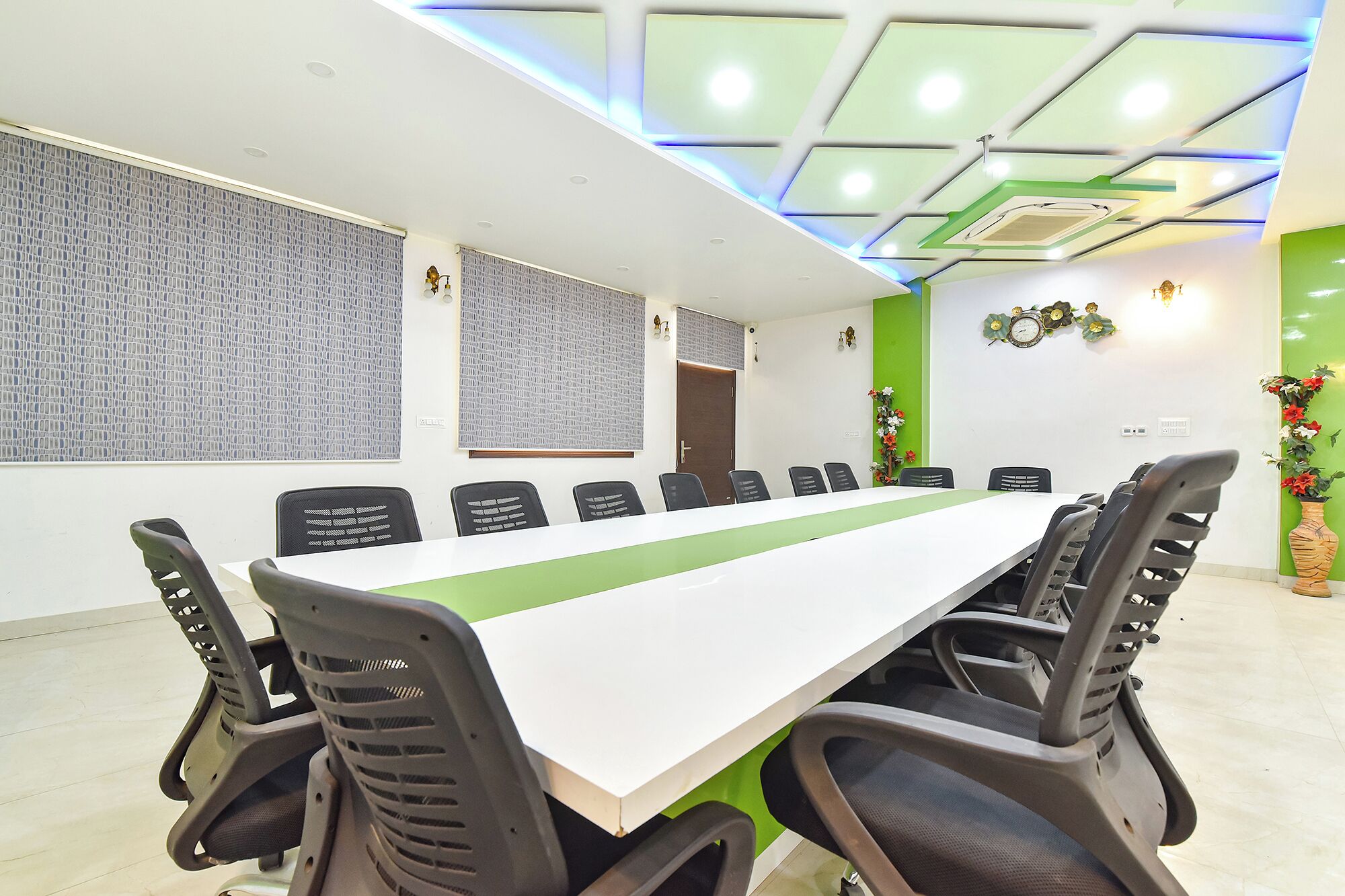 Uma sala de conferência com uma mesa comprida, várias cadeiras e um design moderno no teto.