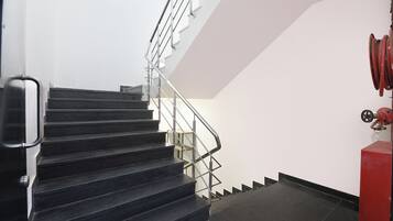 A staircase with metal railings and a red fire hose on the right.