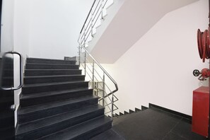 A staircase with metal railings and a red fire hose on the right. - FabHotel D2 Pachim Vihar (New Delhi)
