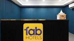 Een receptiebalie met een bord waarop 'fab HOTELS' staat en een decoratief object erboven.