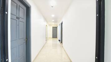 A hallway with a door marked '402' on the left, a mirror on the right, and a door at the end.