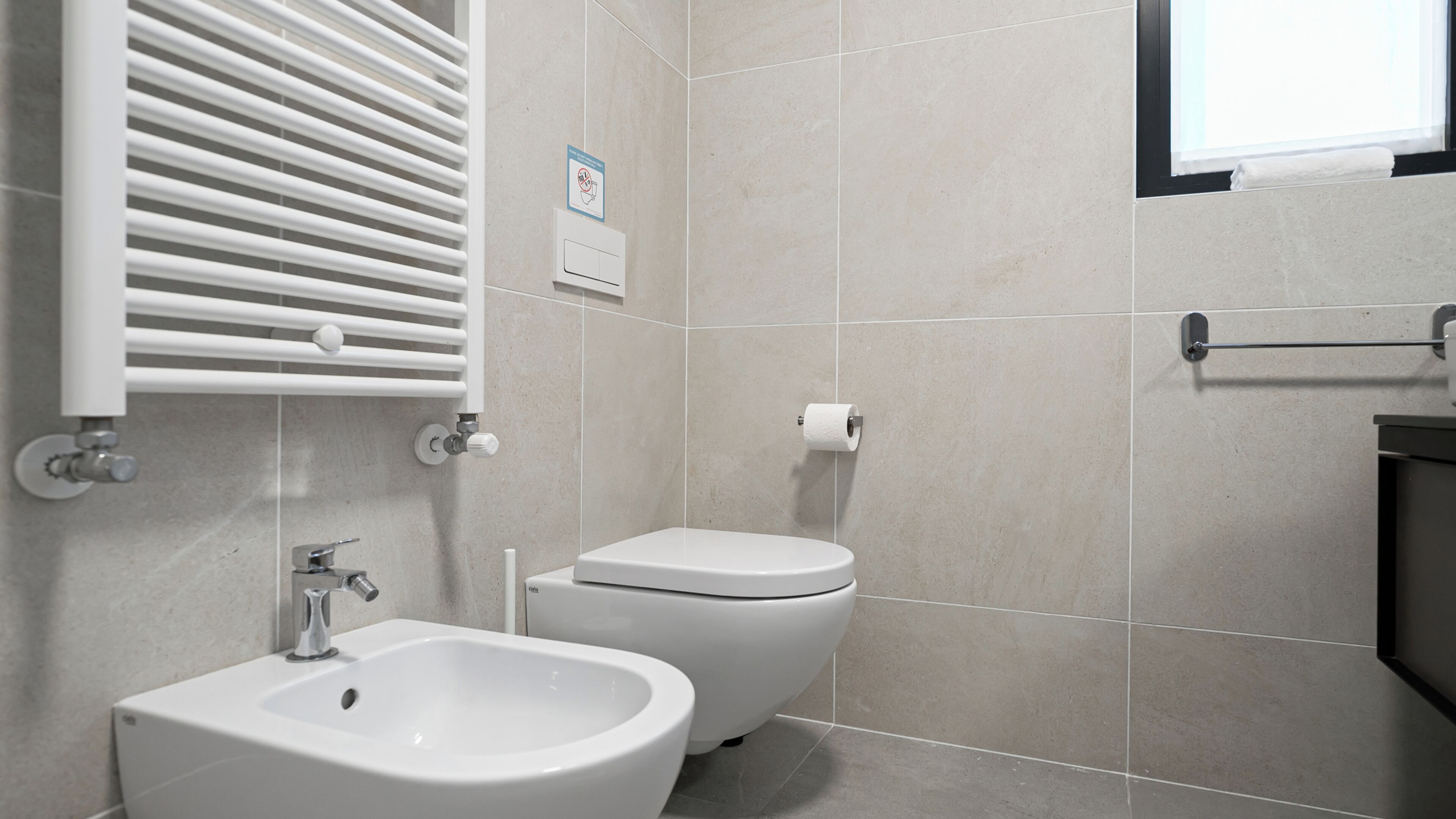 Ein modernes Badezimmer mit einer Bio-Toilette, Toilette und einem Handtuchhalter.