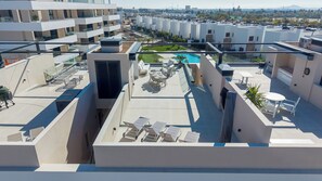 Eine Dachterrasse mit Pool, Sitzgelegenheiten im Freien und Blick auf die Stadtlandschaft.