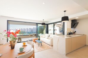 Eine moderne Wohnung mit Essbereich, Sofa, Küche und großen Fenstern.