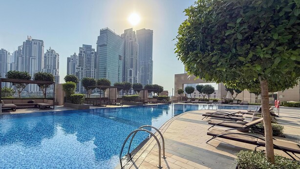 Ein Pool mit Liegestühlen, einer Pergola und Blick auf hohe Gebäude.