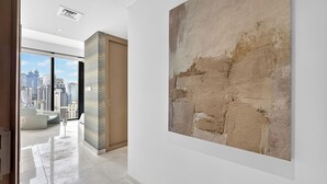 Ein modernes Interieur mit einem großen abstrakten Gemälde, Blick auf die Stadt durch hohe Fenster und einem minimalistischen Design.