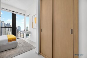 Ein modernes Schlafzimmer mit einem Bett, einem großen Fenster und Blick auf die Stadt.