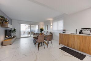 A modern kitchen with a wooden countertop, a dining area with chairs, and a large window. - Penthouse Punta Prima BR3 Valonia (Torrevieja)