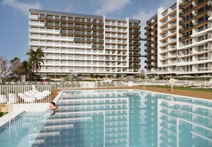 Ein Hotel mit mehreren Etagen, einem Schwimmbad und Außenbereichen mit Sitzgelegenheiten.