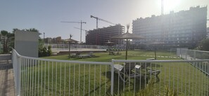 Ein eingezäunter Außenbereich mit Pool, Liegestühlen und einer Baustelle im Hintergrund.