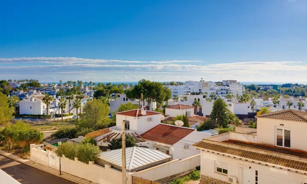A coastal residential area with white buildings, palm trees, and a clear blue sky. - Apartment Santa Ana Villamartin (Orihuela Costa)