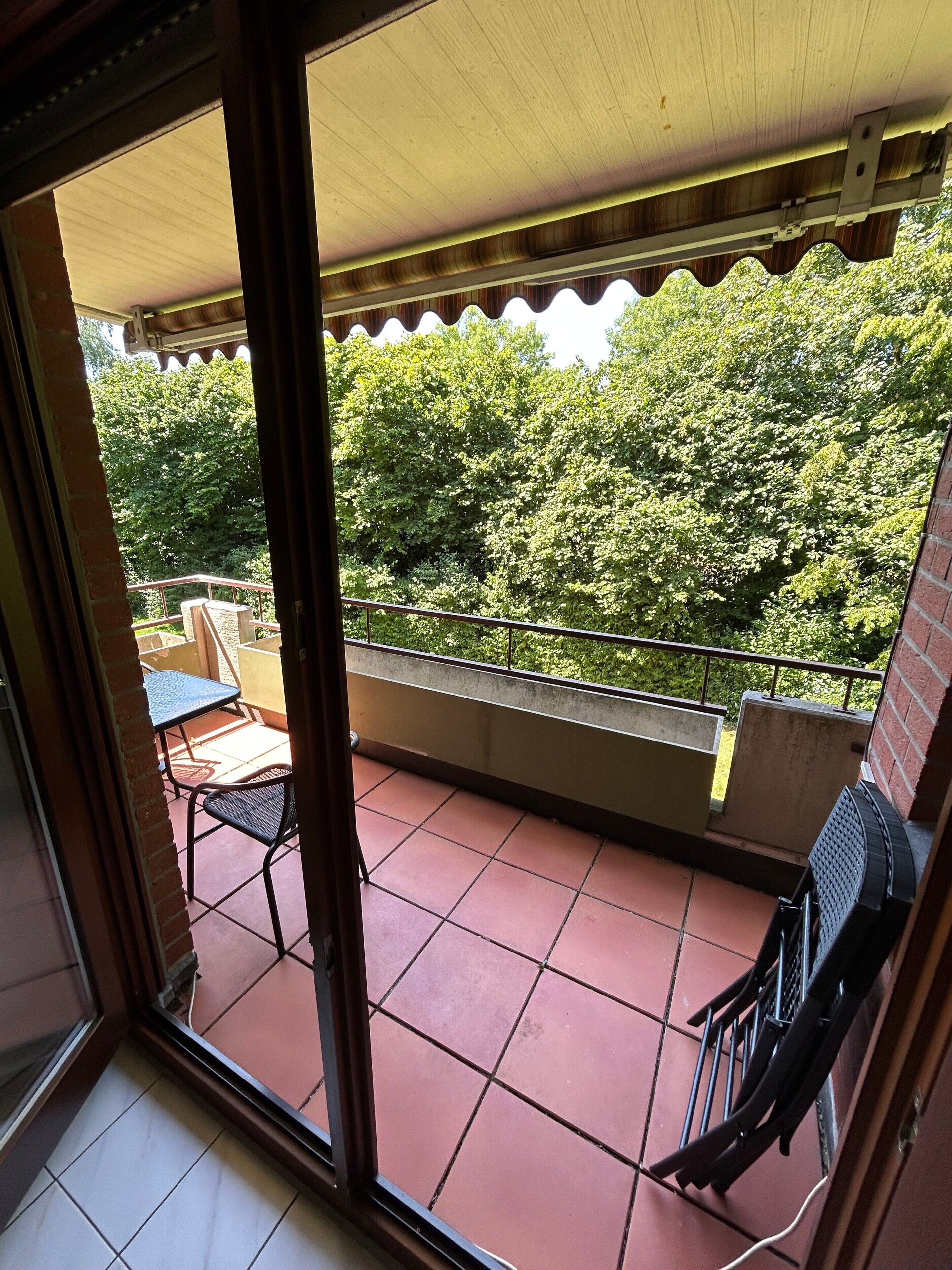 Un balcon avec un sol carrelé, une table et une chaise.