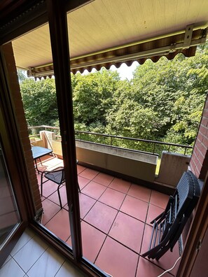 A balcony with a tiled floor, a table, and a chair.