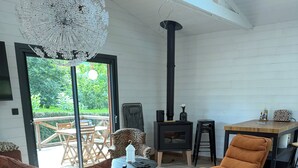 Een moderne woonkamer met een groot raam, een zwarte houtkachel en een bruine bank.