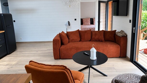 Een moderne woonkamer met een hoekbank, een ronde salontafel en een hanglamp.