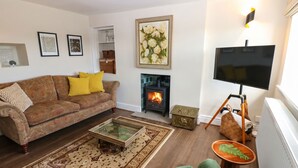 Una sala de estar con sofá, televisor, chimenea y alfombra.