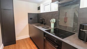 Una cocina moderna con armarios oscuros, horno integrado y un salpicadero de vidrio.