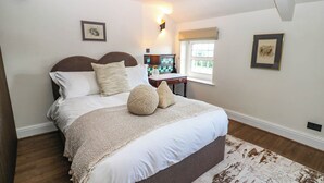 Un dormitorio con cama, mesita de noche, lámpara, ventana y obras de arte en las paredes.