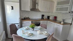 A compact kitchen with white cabinetry, a built-in oven, and a microwave. - Charming Jasmine House in Bromölla (Bromolla)