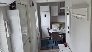 A narrow hallway with a dining area, white cabinets, and a small table with chairs. - Charming Jasmine House in Bromölla (Bromolla)