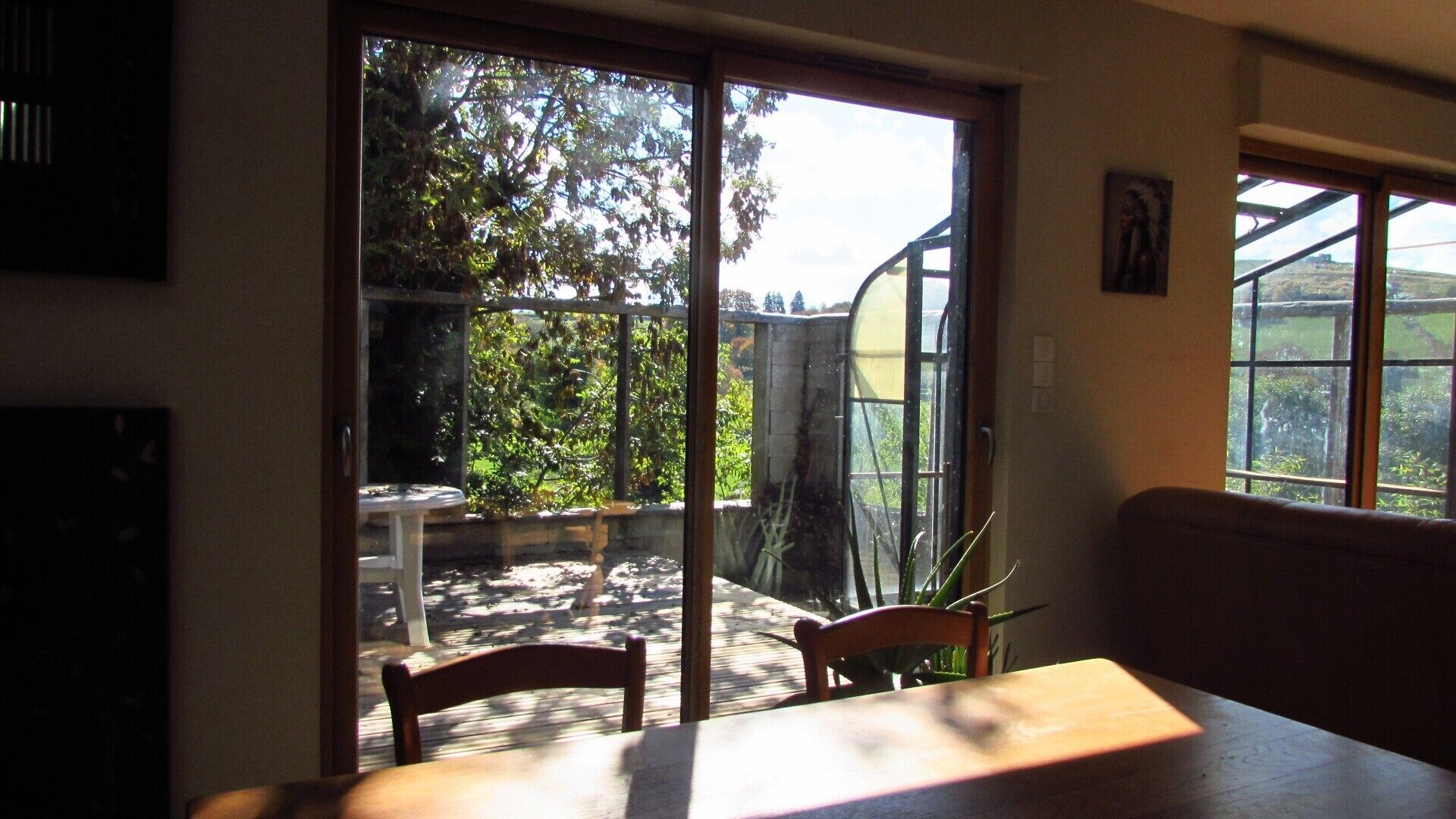 Une pièce dotée d’une porte-fenêtre coulissante donnant sur un jardin, ainsi que d’une table et de chaises.