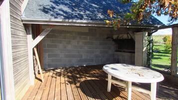 An outdoor patio with a brick wall, a wooden deck, and a round table.