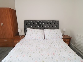 Un dormitorio con cama, dos mesitas de noche, un armario y un radiador.