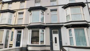 A row of terraced houses with bay windows, a front door, and a small front garden.