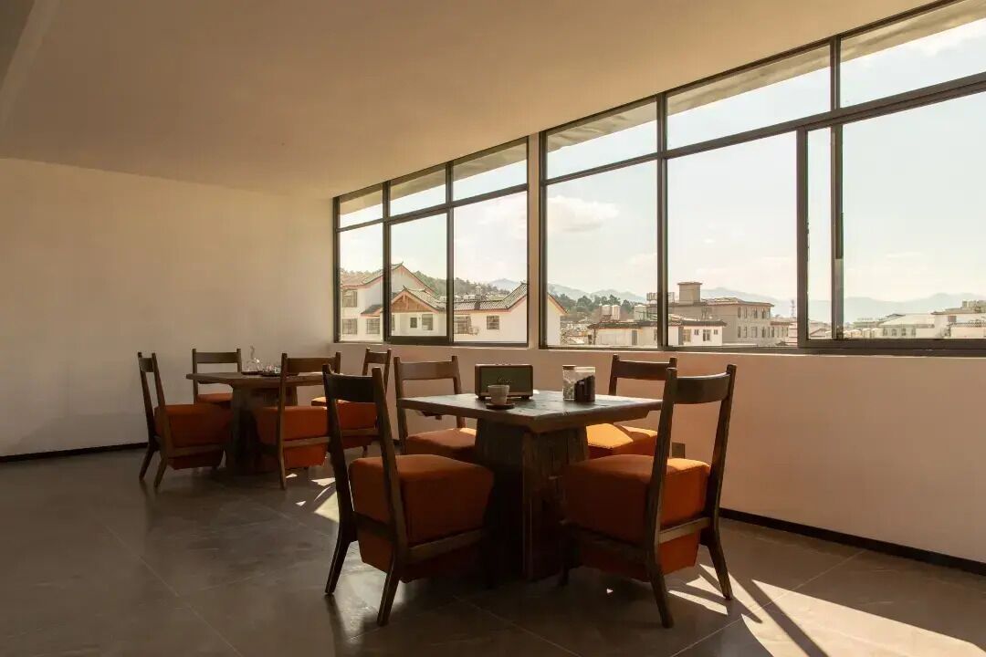 A dining area with a table and chairs, large windows, and a view of buildings.