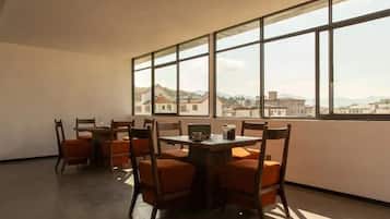 A dining area with a table and chairs, large windows, and a view of buildings.