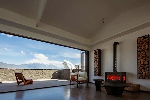 Un interior moderno con chimenea, zona de estar y un ventanal que da a un paisaje nevado.
