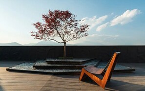 Eine Holzterrasse mit einem Baum und einem Stuhl.