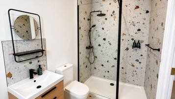 A bathroom with a white sink, a toilet, a shower with a glass door, and a mirror with a circular frame.