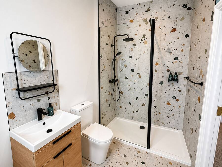 A bathroom with a white sink, a toilet, a shower with a glass door, and a mirror with a circular frame.
