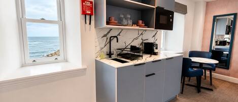 Una cocina compacta con estufa integrada, un lavamanos y una ventana con vistas al mar.
