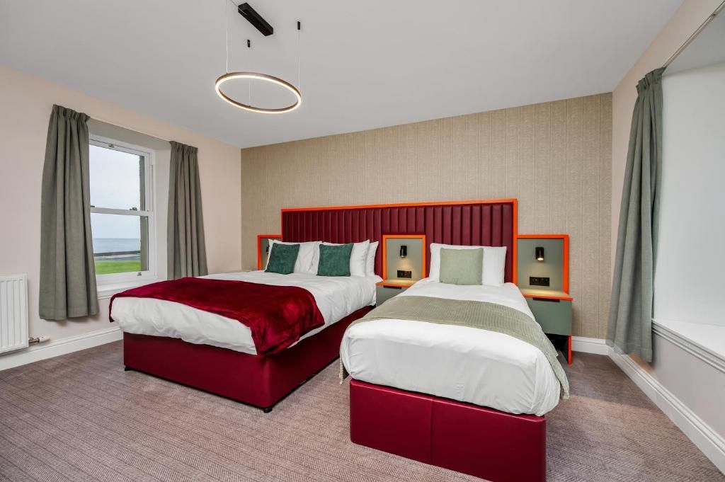 Een hotelkamer met twee bedden, een groot raam en uitzicht op de omgeving.