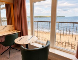 A room with a view of the beach, a table, and two chairs. - The View by BIDE Hotels (Thurso)