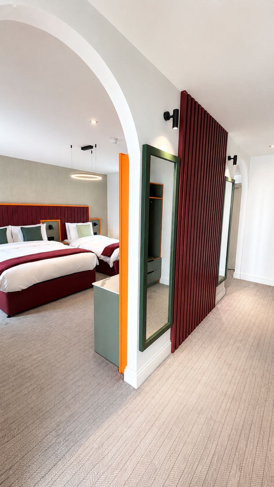 A hotel room with a large bed, a mirror, and a wardrobe.